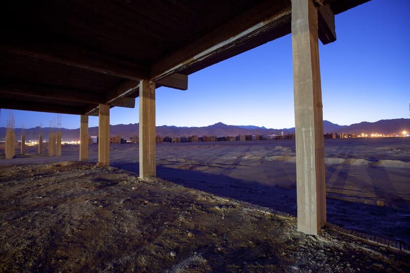 Concrete columns holding an empty roof deck at dusk, mountains silhouetted beyond