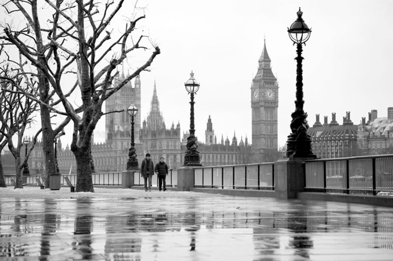 Wet riverside walk in melting snow, walkers under bare trees, Big Ben and Parliament in the distance