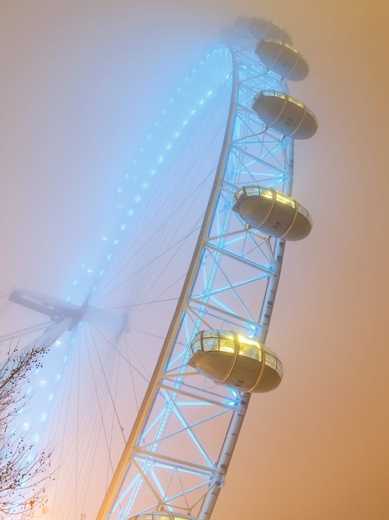 Capsules of the London Eye lit gold in dense fog, seen close from below
