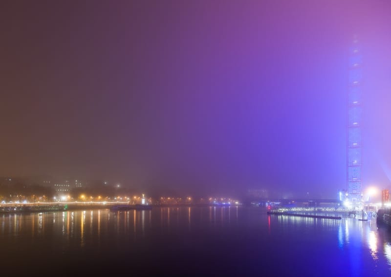 Fog glowing violet over the Thames at night, riverside lights fading into the haze