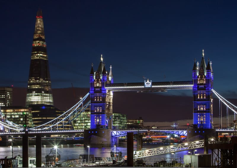 The Shard and Tower Bridge lit blue at night, traffic trails crossing the river