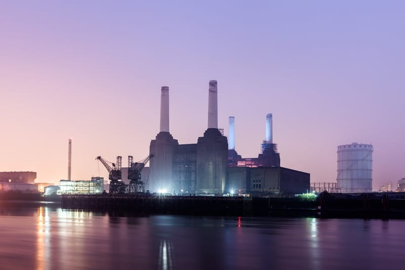Battersea Power Station's four chimneys lit at dusk across the Thames