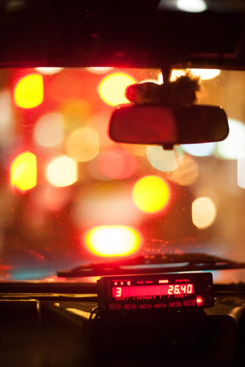 Night-time taxi ride through London — meter and mirror against a windscreen full of blurred city lights