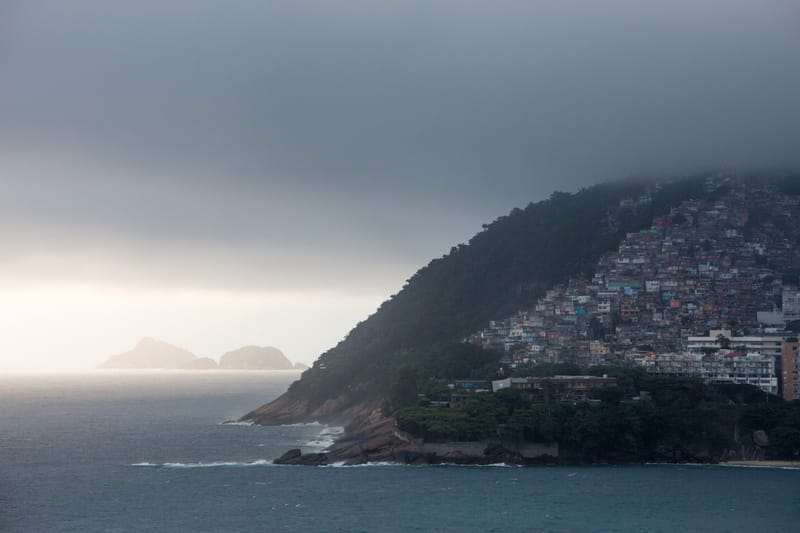 Cloud rolling over the steep hillside of Vidigal above the sea, islands offshore, Rio de Janeiro