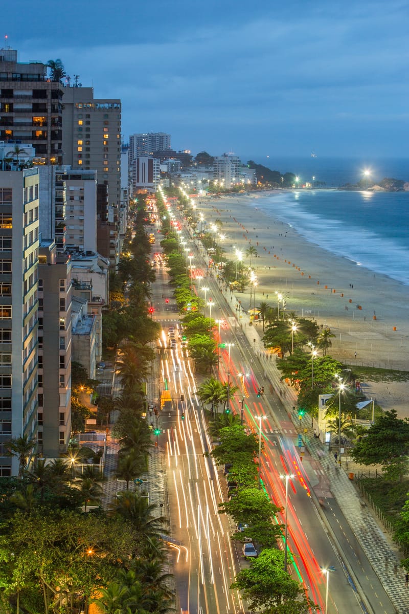 Beachfront avenue at dusk from above, traffic light trails running beside the sand, Rio de Janeiro