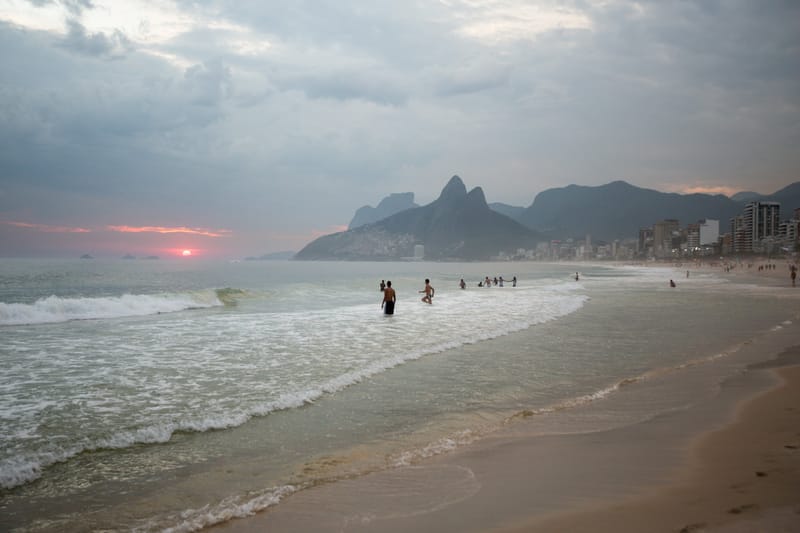 Bathers in the surf at dusk below the silhouette of the Two Brothers, Ipanema, Rio de Janeiro