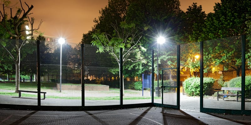 A caged games court under floodlights at night