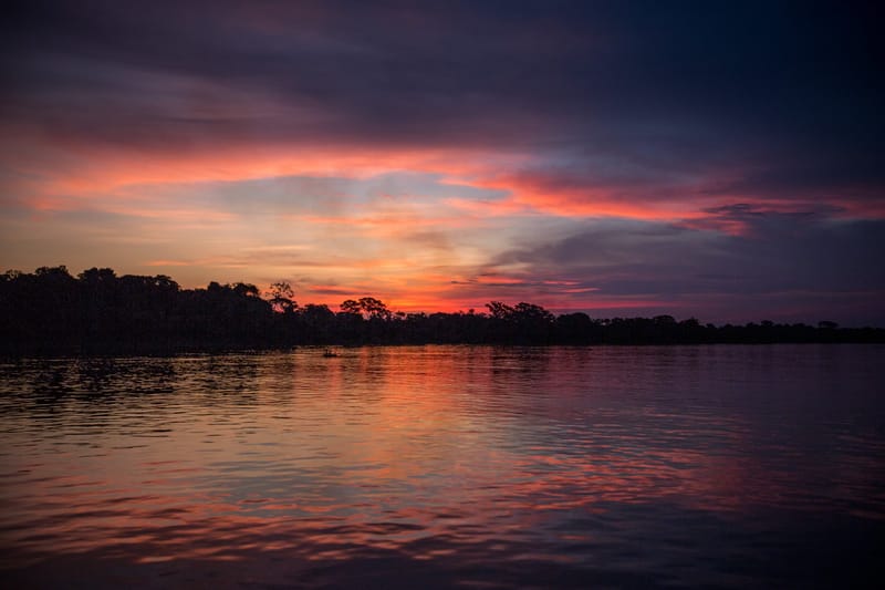 Sunset burning beneath dark clouds over the waters of the Pantanal, Brazil