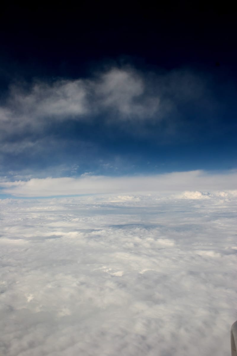 Towering clouds over a sea of cloud, seen from an aircraft window