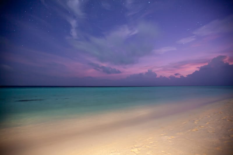 A star-flecked violet sky over a pale lagoon at dusk, Maldives